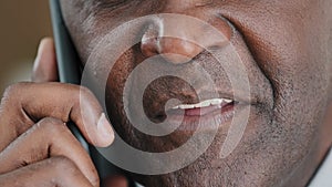 Unknown half face part old wrinkled emotional businessman African mature man talking on mobile phone unrecognizable boss