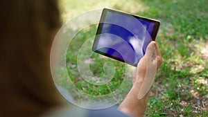 Unknown hands holding tablet on nature. Unrecognizable man have gadget on picnic