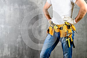 unknown handyman with hands on waist and tool belt with construc