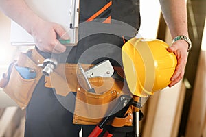 Unknown handyman with hands on waist and tool belt with construction tools against grey background. DIY tools and manual