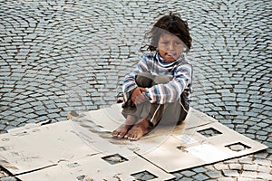 Unknown homeless kid sitting on the street