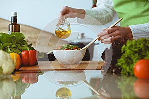 Unknown human hands cooking in kitchen. Woman is busy with vegetable salad. Healthy meal, and vegetarian food concept