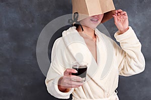 Unknown lady wearing bathrobe with closed face drinking alcohol