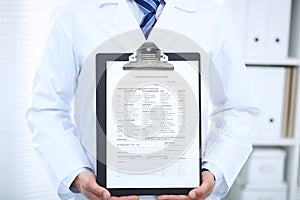 Unknown male doctor standing straight while holding medical form. Medicine and health care concept