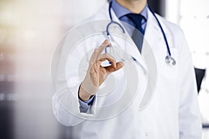 Unknown male doctor standing straight with OK sign in sunny clinic, closeup. Perfect medical service in hospital