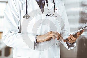 Unknown male doctor using tablet computer in clinic near his working place, closeup. Perfect medical service in hospital
