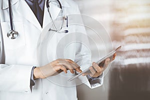 Unknown male doctor using tablet computer in sunny clinic, closeup. Perfect medical service in hospital. Medicine and