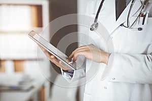 Unknown male doctor using tablet computer in sunny clinic, closeup. Perfect medical service in hospital. Medicine and