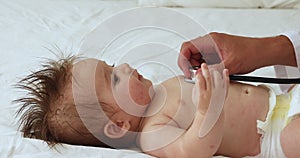 Unknown male paediatrician holds stethoscope listens heartbeat of newborn