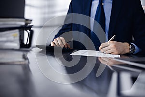 Unknown man accountant in blue blazer use calculator and computer with holding pen on while staying at home during covid