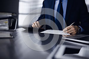 Unknown man accountant in blue blazer use calculator and computer with holding pen on while staying at home during covid