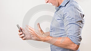 Unknown man holding his smart phone yelling in frustration at bad news