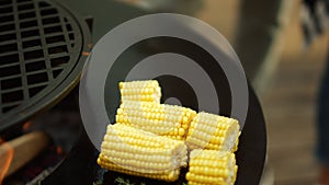 Unknown man preparing vegetarian food outside. Fresh corn grilling on bbq grill