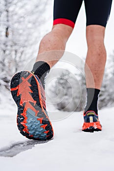 Unknown man running in snow in winter day close up on shoe sneakers