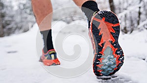 Unknown man running in snow in winter day close up on shoe sneakers
