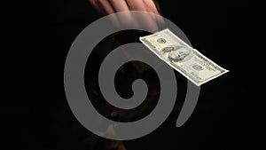 Unknown man throws dollars at black reflecting
