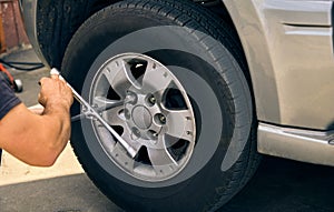 An unknown person dismantles a damaged car wheel for service