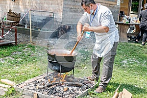 An unknown person prepares a traditional Romanian food prepared at the cauldron on the open fire