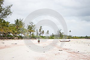 Unknown person walking alone on the beach. Tourist from the back on low tide beach, Africa. Tropical vacations on Indian Ocean.