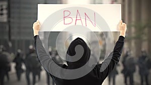 Unknown protester holds a placard with BAN text