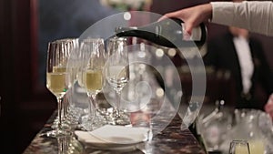 Unknown waiter is pouring champagne into glasses on the bar back. Luxury restaurant or hotel. Wedding and birthday