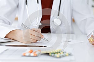 Unknown woman-doctor fills up prescription form. close-up. Panacea and life save, prescribe treatment, legal drug store