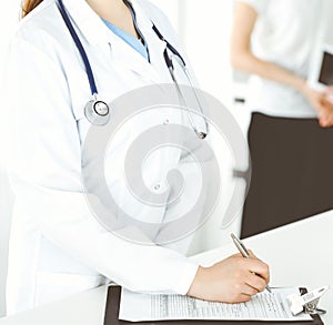 Unknown woman-doctor or internal student at work with patient and physician at the background. Female practitioner