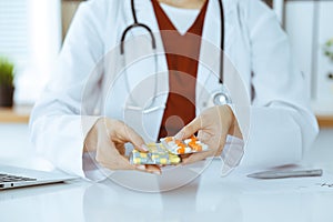 Unknown woman-doctor offering pack of different tablet blisters, close-up. Medicine concept