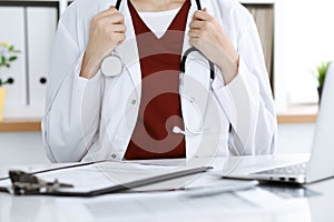 Unknown woman-doctor with a stethoscope in the hands. Physician is ready to examine a patient, close-up of hands