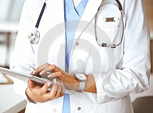 Unknown woman-doctor using tablet computer, close-up. Medicine concept