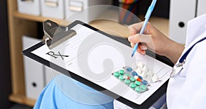 Unknown woman doctor at work at hospital. Pills at medical clipboard. Young female physician write prescription or