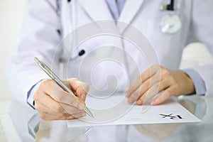 Unknown woman doctor at work at hospital. Pills at medical clipboard. Young female physician write prescription or