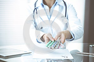 Unknown woman doctor at work at hospital. Pills at medical clipboard. Young female physician write prescription or