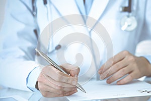 Unknown woman doctor at work at hospital. Pills at medical clipboard. Young female physician write prescription or