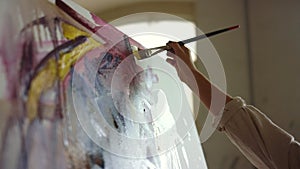 Unknown woman painting in art studio. Talented painter holding brush indoors.