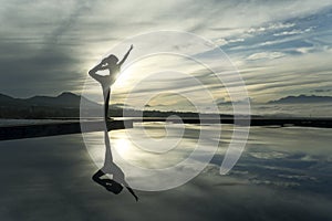 Unknown woman practicing yoga at the poolside