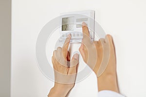 Unknown woman using smart home technology connected appliances device on wall, monitoring energy security heating system, digital