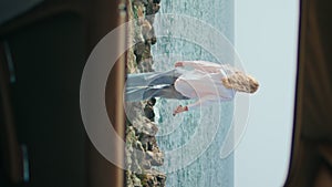 Unknown woman walking coast with phone view through car window vertical oriented