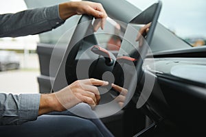 Unknown young man hand which typing needed coordinates on navigator touchscreen inside his modern car close up