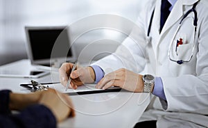 Unknown young woman patient discuss the results of her medical tests with a doctor, while sitting at the desk in a