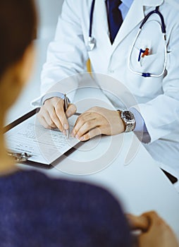 Unknown young woman patient discuss the results of her medical tests with a doctor, while sitting at the desk in a