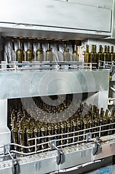 Unlabeled glass bottles in bottling machine at modern winery