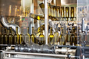 Unlabeled glass bottles in bottling machine at modern winery