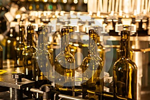 Unlabeled glass bottles in bottling machine at modern winery