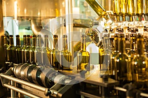 Unlabeled glass bottles in bottling machine at modern winery