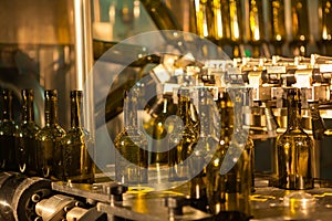 Unlabeled glass bottles in bottling machine at modern winery