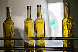 Unlabeled glass bottles in bottling machine at modern winery