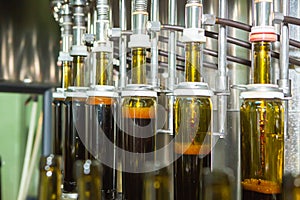 Unlabeled glass bottles in bottling machine at modern winery