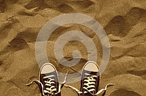 Unlaced pair of sneakers on beach, retro design, top view