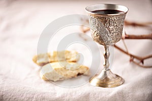 Unleavened bread, chalice of wine, silver kiddush wine cup on canva background. Communion still life. Christian communion concept